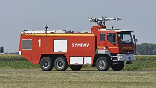 Airport foam fire tender beside a grass airfield