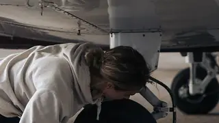 Student pilot inspecting a small aircraft wheel at a flight school