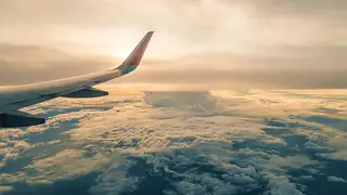 Storm clouds building beyond an airliner wing in flight