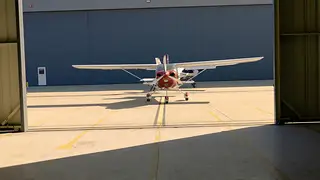 Light aircraft leaving a hangar on a sunny day