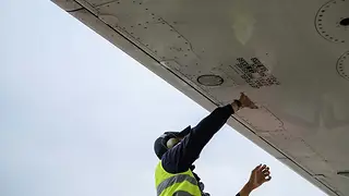 Engineer in safety vest under an aircraft